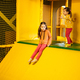 Siblings sliding at yellow playground park. Sisters in active entertaiments. - PhotoDune Item for Sale
