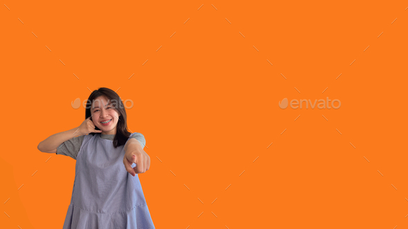 Bright young asian woman inviting to call isolated on orange background - Stock Photo - Images
