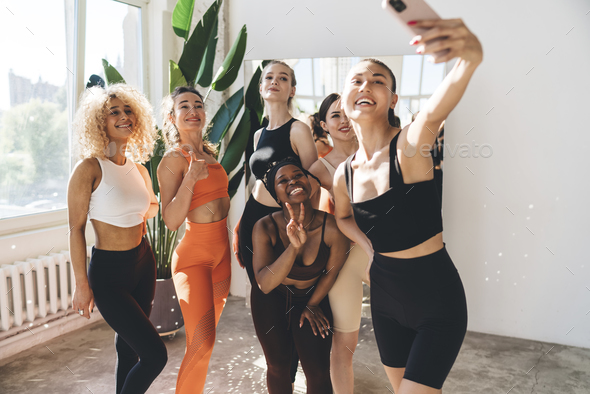 Group of positive sportswomen taking selfie in gym - Stock Photo - Images