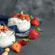 Greek yogurt, nuts and strawberries in a glass jars on grey table close up, copy space - PhotoDune Item for Sale
