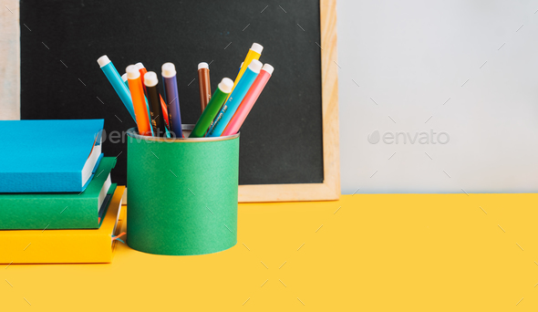 School supplies with books and chalk board on yellow background - Stock Photo - Images