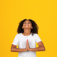 Smiling adolescent curly girl in white t-shirt looking up, praying gesture - PhotoDune Item for Sale