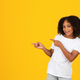 Smiling adolescent curly african american girl in white t-shirt points fingers at empty space - PhotoDune Item for Sale