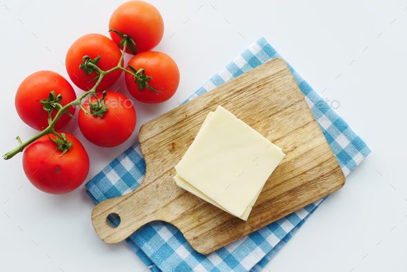Slicing cheese into pieces and tomato on table  - Stock Photo - Images