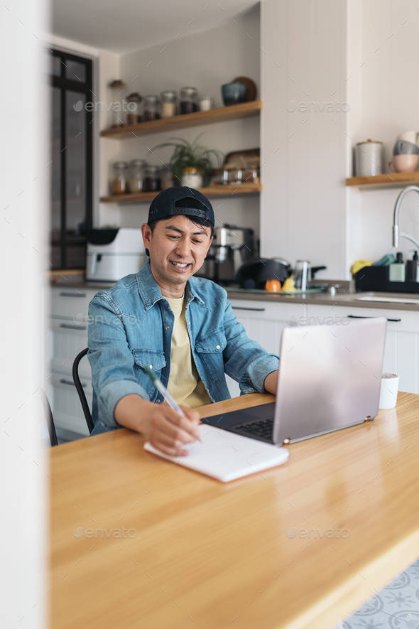 Cheerful asian man working from home - Stock Photo - Images