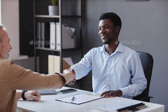 Black man shaking hands with senior candidate at job interview