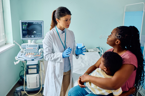 Female pediatrician talking to black mother and son in medical examination room. - Stock Photo - Images