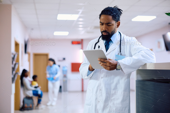 Black male doctor using digital tablet at the clinic. - Stock Photo - Images