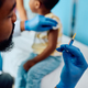Close up of black doctor preparing syringe for vaccination of a child at medical clinic. - PhotoDune Item for Sale