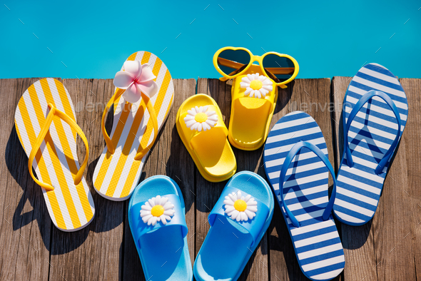 Beach flip-flops and sunglasses on wooden planks near swimming pool - Stock Photo - Images