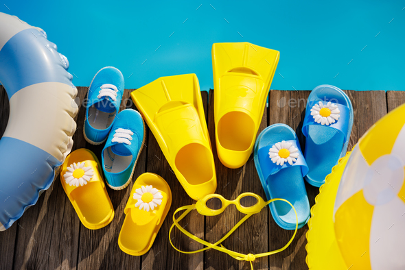 Beach flip-flops and sunglasses on wooden planks near swimming pool - Stock Photo - Images