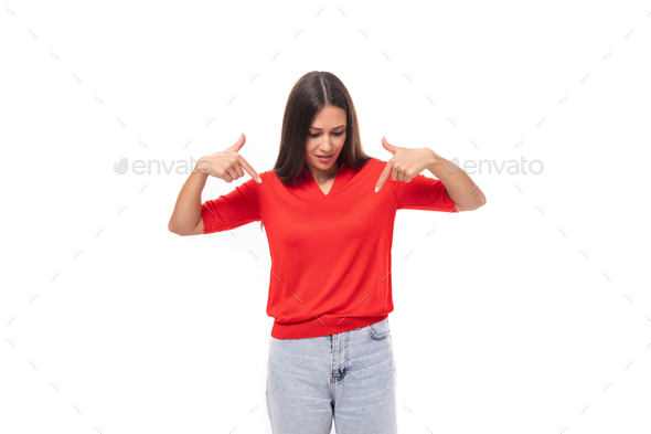 young inspired caucasian brunette woman in a red short sleeve shirt points with her hands to the - Stock Photo - Images