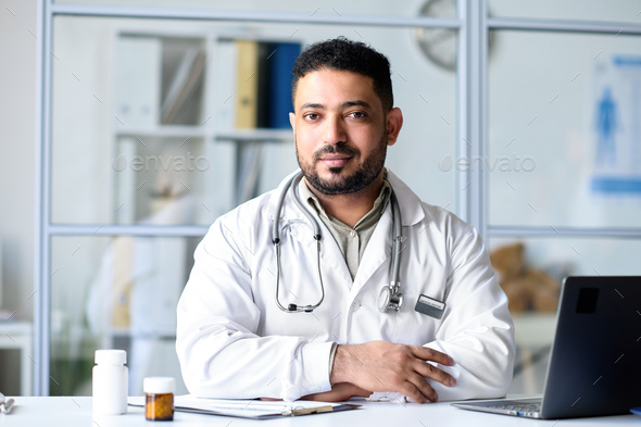 Professional doctor sitting at his workplace in office - Stock Photo - Images