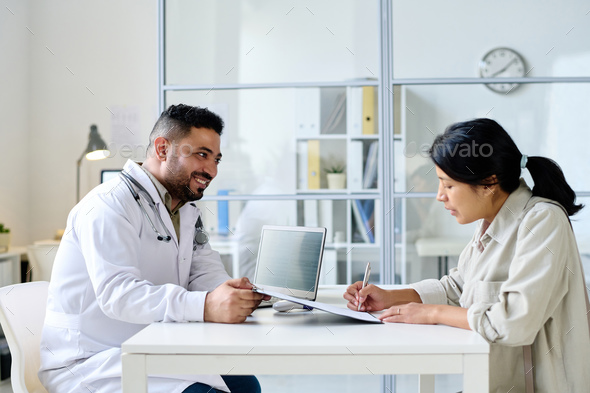 Woman signing agreement for treatment in hospital - Stock Photo - Images