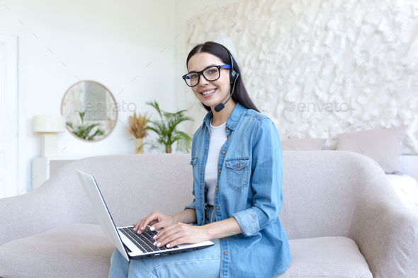 Portrait of a young businesswoman, a freelancer who works from home online in a headset. Sitting on - Stock Photo - Images