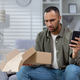 A worried young Hispanic man received a wrong and damaged package, an online store order, at home - PhotoDune Item for Sale