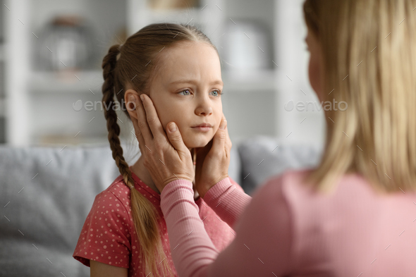Childhood Problems Concept. Young mother comforting her sad little daughter at home - Stock Photo - Images