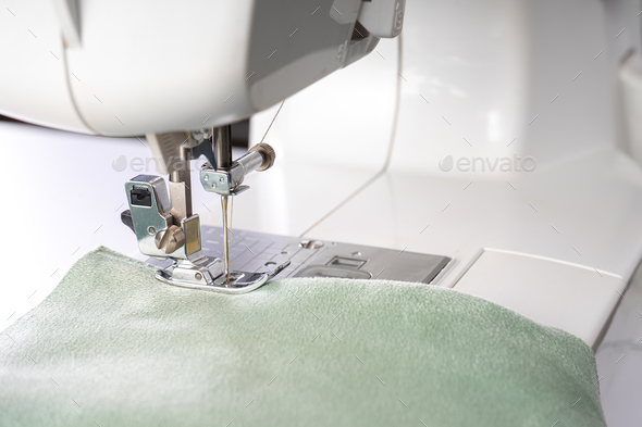 Modern sewing machine presser foot with green fabric and thread, closeup, macro - Stock Photo - Images