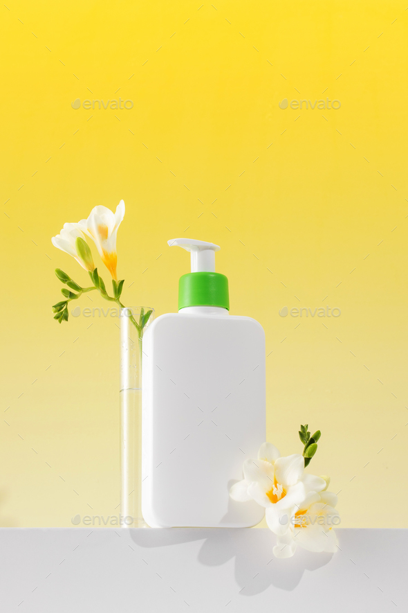 A mockup of a dispenser with a cosmetic skin care product for the face and body with flowers. - Stock Photo - Images