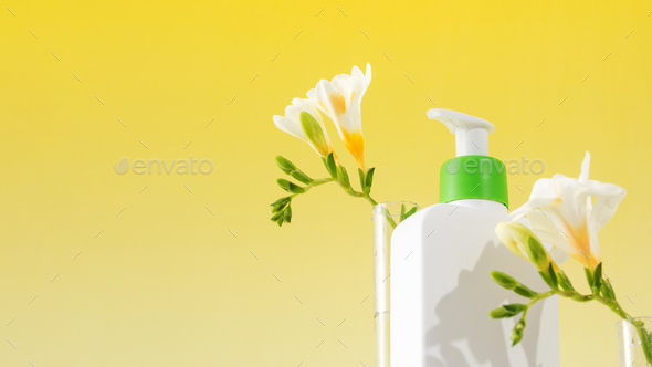 A mockup of a dispenser with a cosmetic skin care product with flowers. Copy space - Stock Photo - Images