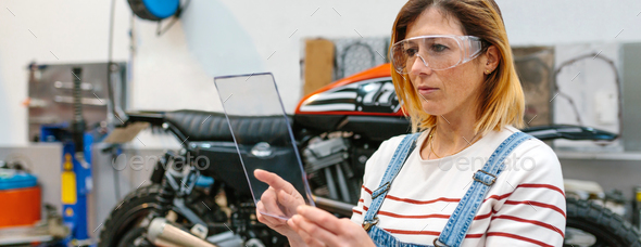 Female mechanic with security glasses holding transparent tablet - Stock Photo - Images