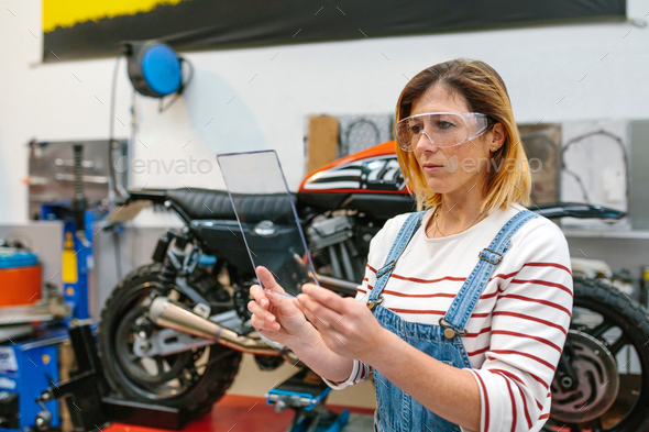 Female mechanic with security glasses holding transparent tablet - Stock Photo - Images