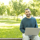 Young Caucasian happy and smiling man working on laptop outdoors, looking at the camera - PhotoDune Item for Sale