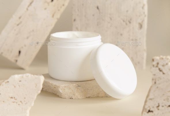 Opened white cream jar with a lid near biege stones close up. Cosmetic Mockup - Stock Photo - Images