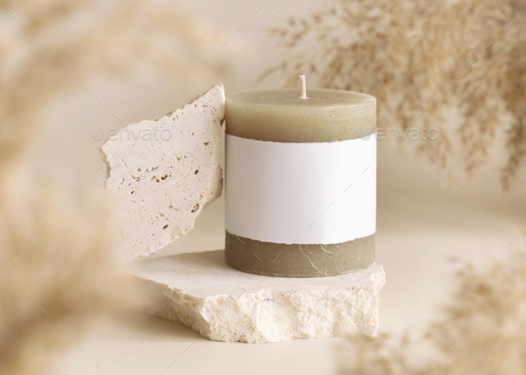 Candle with label on beige stone near dried pampas grass close up, copy space, mock up - Stock Photo - Images