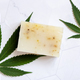 Craft soap bar near green cannabis leaves on white marble table. Cosmetic Mockup - PhotoDune Item for Sale
