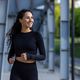 Young beautiful hispanic woman with curly hair jogging near stadium, woman in tracksuit smiling - PhotoDune Item for Sale