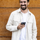 Confident handsome young guy texting with his phone and looking at camera. Happy and relaxed man - PhotoDune Item for Sale