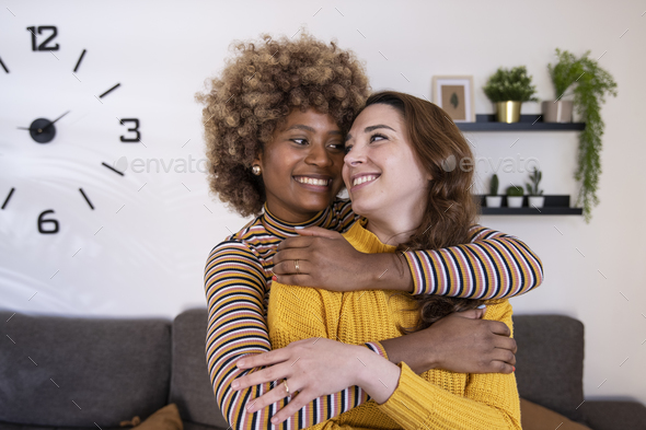 Beautiful And Cheerful Multiracial Lesbian Couple Hugging And Looking