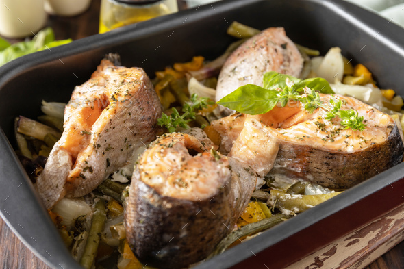 Healthy baked fish salmon steaks with basil green beans and sweet peppers on a rustic table