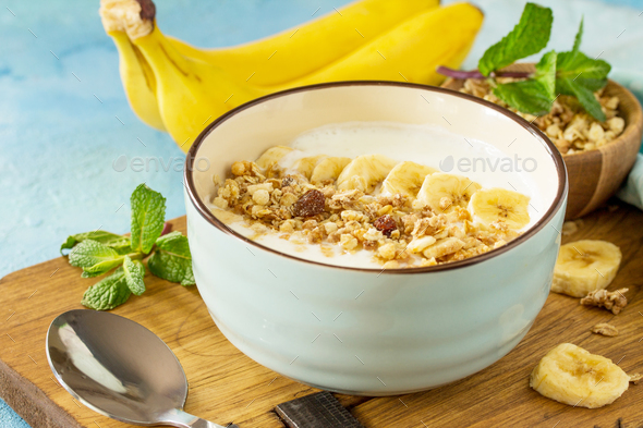 Granola with yogurt, chocolate and banana on blue concrete or stone table.   - Stock Photo - Images