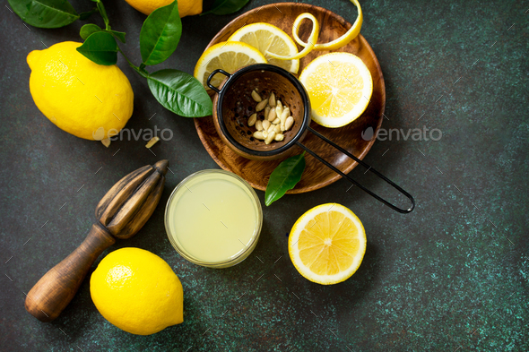 Cold drink with freshly squeezed lemon juice and fresh lemons on a dark stone table.  - Stock Photo - Images