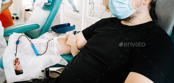 Middle-aged man donates blood in medical laboratory. International Blood Donation Day. - Stock Photo - Images