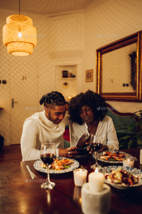 African american couple having romantic date and using smartphone at home - Stock Photo - Images