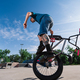 A mature tattooed professional bike rider is balancing on on wheel with his bmx in a skate park. - PhotoDune Item for Sale