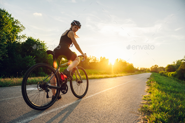 Portrait of a woman riding a bike during a sport cycling race outside of the city - Stock Photo - Images