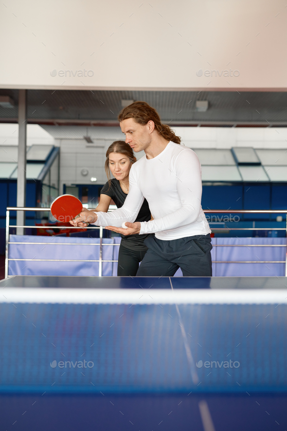 Adult woman instructor teaching male student to play table tennis at sport club - Stock Photo - Images