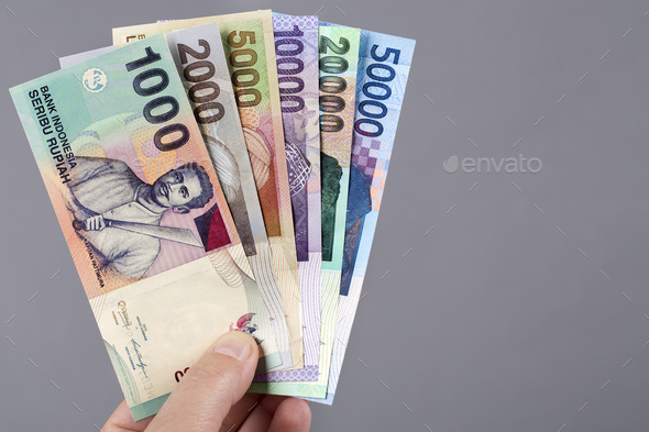 Old Indonesian money in the hand on a gray background - Stock Photo - Images
