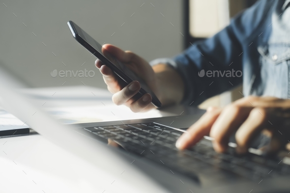 Close up of businessman is analyzing the stock marketing on smartphone and laptop. - Stock Photo - Images
