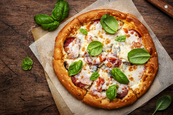 Pizza with spicy salami sausage, mozzarella cheese, tomato sauce and green basil - Stock Photo - Images