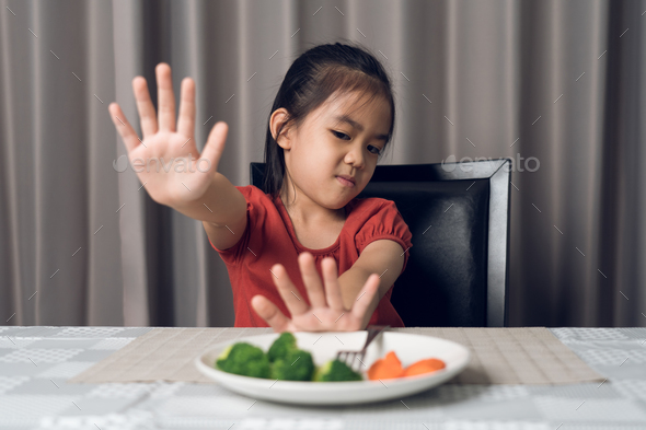 Little cute kid girl refusing to eat healthy vegetables. Children do not like to eat vegetables. - Stock Photo - Images