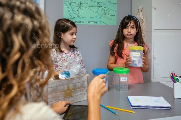 Student looking at teacher while holding sorting waste bin - Stock Photo - Images