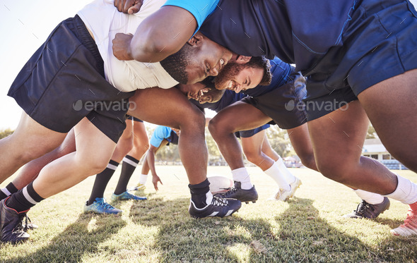 Below two opponent rugby teams contesting a scrum during a match outside on a field. Rugby players