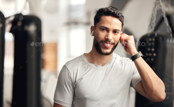 Portrait of one confident young hispanic man listening to music with wireless bluetooth earphones t