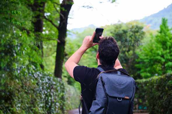 Tourist taking picture of a forest in Kyoto using his mobile phone. - Stock Photo - Images