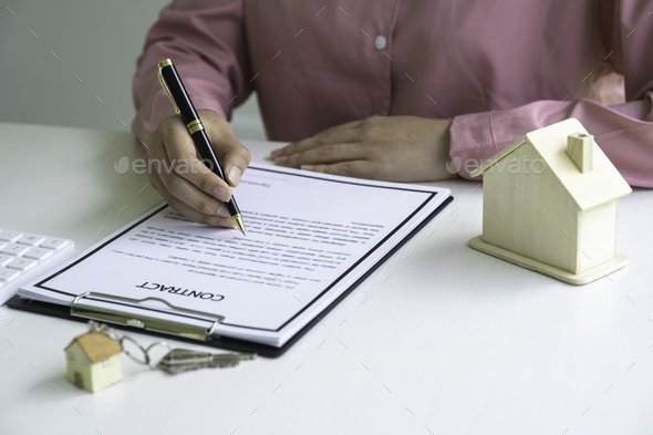 Real estate agent holding home and signing contract about agreement of real property on desk, busine